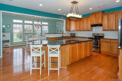 An ideal Kitchen designed for family and entertaining ~ large granite island, tons of storage and counterspace, gorgeous tile backsplace, Breakfast Bar, walk-in Pantry, stylish lighting.