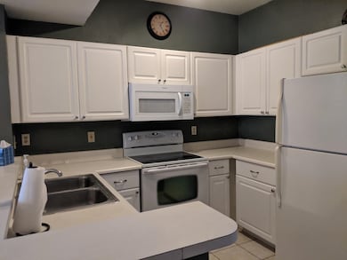 Kitchen featuring white appliances, white cabinetry, and light countertops