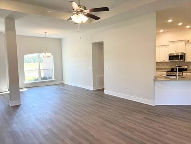 Unfurnished living room with dark wood-style floors, ceiling fan, and a chandelier