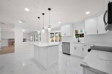 Kitchen featuring crown molding, a kitchen island, light marble finish flooring, light stone countertops, and tasteful backsplash