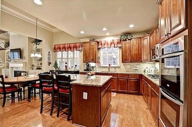 Kitchen featuring light wood-style flooring, a center island, appliances with stainless steel finishes, a kitchen breakfast bar, and ornamental molding
