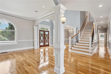 Foyer entrance featuring healthy amount of natural light, stairway, ornamental molding, arched walkways, and wood finished floors