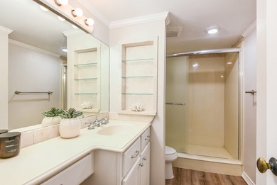 Full bathroom featuring crown molding, vanity, light wood-type flooring, and a shower stall