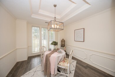 Coffered ceiling in the formal dining room with beautiful chandelier. Wonderful wainscote and chair molding. Bright and light dining room where family memories will be made.