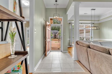 Entryway with a chandelier, light tile patterned floors, and crown molding