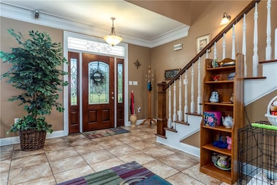 Entryway with stairway, ornamental molding, and tile patterned floors