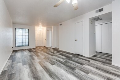 Unfurnished living room featuring a textured ceiling, a ceiling fan, and light wood-style flooring