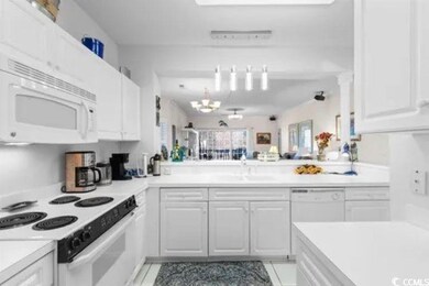 Kitchen featuring a notable chandelier, white appl