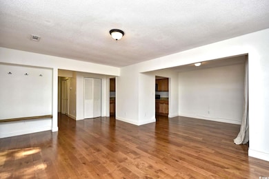 Empty room featuring a textured ceiling, wood fini