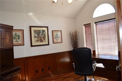 Office has wood wainscoating, vaulted ceilings, ceiling fan, wood floors