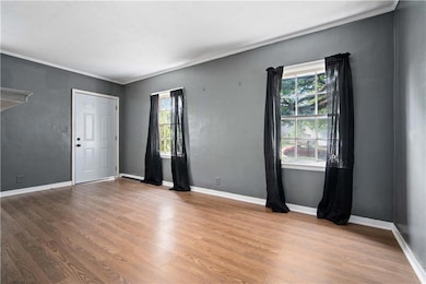 Unfurnished room featuring wood finished floors, crown molding, and baseboards