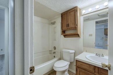 Bathroom with bathing tub / shower combination, vanity, a textured ceiling, and light tile patterned floors
