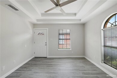Entrance foyer featuring a tray ceiling, a ceiling fan, and wood finished floors