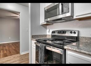 Kitchen with light stone countertops, wood finishe