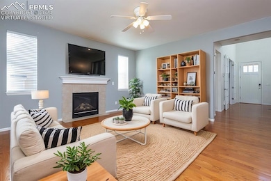 Living room with a tiled fireplace, ceiling fan, a