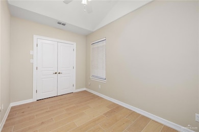 Unfurnished bedroom featuring light wood-style floors, baseboards, lofted ceiling, a closet, and ceiling fan