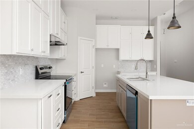 Kitchen featuring under cabinet range hood, white cabinetry, a sink, and appliances with stainless steel finishes