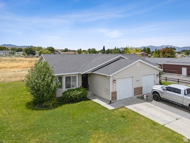 Ranch-style home featuring a garage, a front yard, concrete driveway, roof with shingles, and a mountain view
