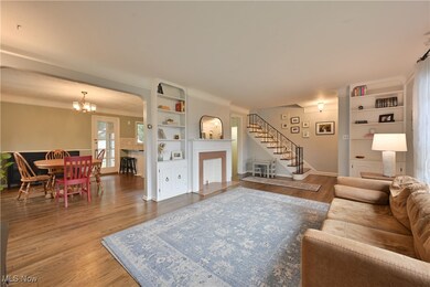 Living room featuring built in shelves, wood finished floors, stairway, a fireplace, and a chandelier