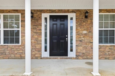 Entrance to property with a porch and stone siding