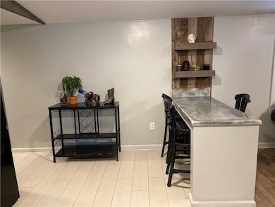 Indoor wet bar featuring stainless steel countertops, light wood-style floors, and open shelves