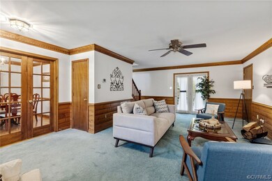 Carpeted living room with ceiling fan, crown moldi
