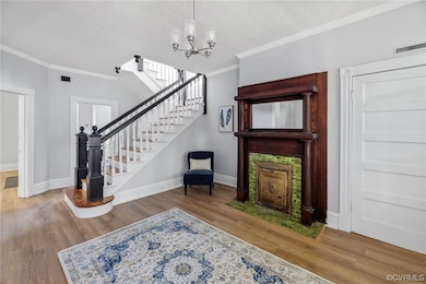 Interior space with ornamental molding, a notable chandelier, and light hardwood / wood-style floors