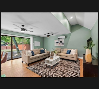 Living area with an AC wall unit, ceiling fan, wo
