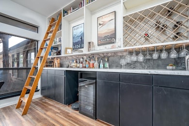 Bar with light wood finished floors, a bar, wine c