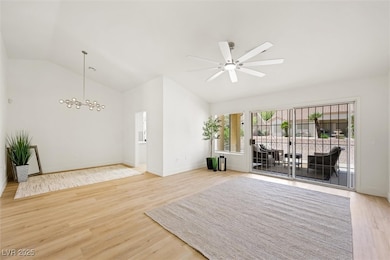 Unfurnished room featuring vaulted ceiling, light wood finished floors, a chandelier, and ceiling fan