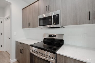 Kitchen with stainless steel appliances, modern cabinets, light wood finished floors, light stone counters, and decorative backsplash