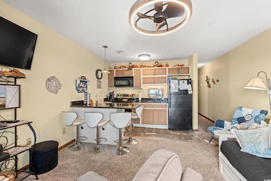 Living room with light carpet, ceiling fan, and a 