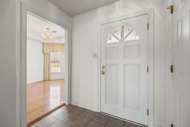 Tiled entrance foyer featuring a chandelier and baseboards