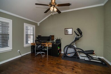 Office with wood floors and plantation shutters.