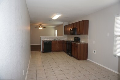 Kitchen featuring tasteful backsplash, black appliances, light tile patterned floors, a ceiling fan, and a peninsula