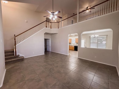 Unfurnished living room with a ceiling fan, a high ceiling, stairs, a chandelier, and arched walkways