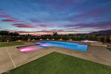 Pool at dusk featuring a pool with connected hot t