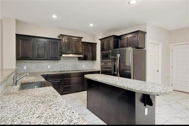 Kitchen with stainless steel appliances, light tile floors, dark brown cabinetry, and backsplash