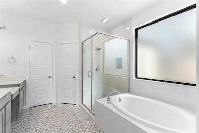 Spa-like ensuite with a soaking tub, separate glass shower, dual sinks, and walk-in closet.