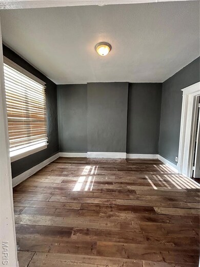 Spare room with a textured ceiling and dark wood-style floors