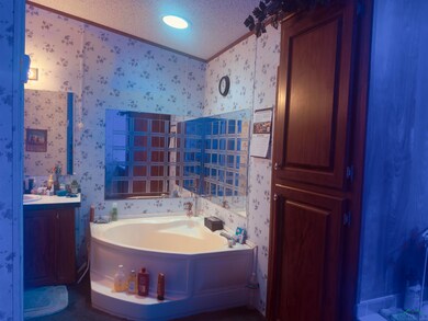 Bathroom with wallpapered walls, a bath, crown molding, vanity, and a textured ceiling