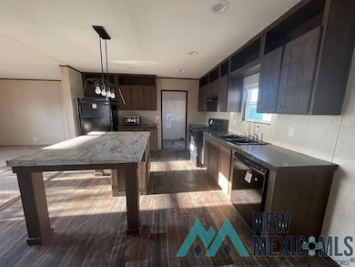 Kitchen with dark countertops, black appliances, dark wood finished floors, pendant lighting, and dark brown cabinetry