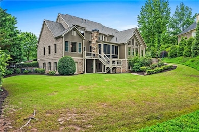 Back of house with a sunroom, stairway, a lawn, and brick siding