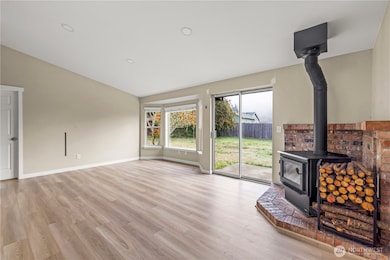 Another angle of the main living space highlighting the wood-burning stove and brick surround. Perfect for keeping warm through PNW winters while enjoying backyard views.