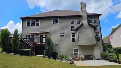 Rear view of house with a deck, a patio, a lawn, a chimney, and stairs