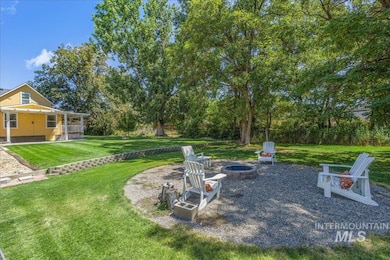 View of grassy yard featuring an outdoor fire pit and covered porch