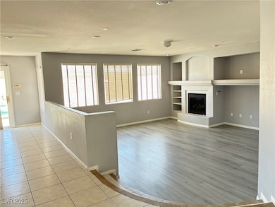 Unfurnished living room featuring baseboards, wood