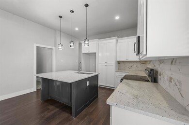 Kitchen with electric range oven, sink, a center island with sink, and dark wood-type flooring