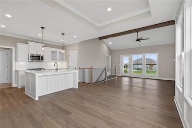 Kitchen with glass insert cabinets, white cabinets, open floor plan, tasteful backsplash, and decorative light fixtures