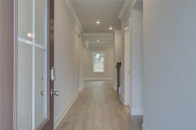Corridor featuring ornamental molding, light wood-style flooring, and baseboards